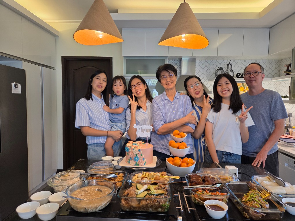 Family making funny faces and playful peace signs around the birthday table