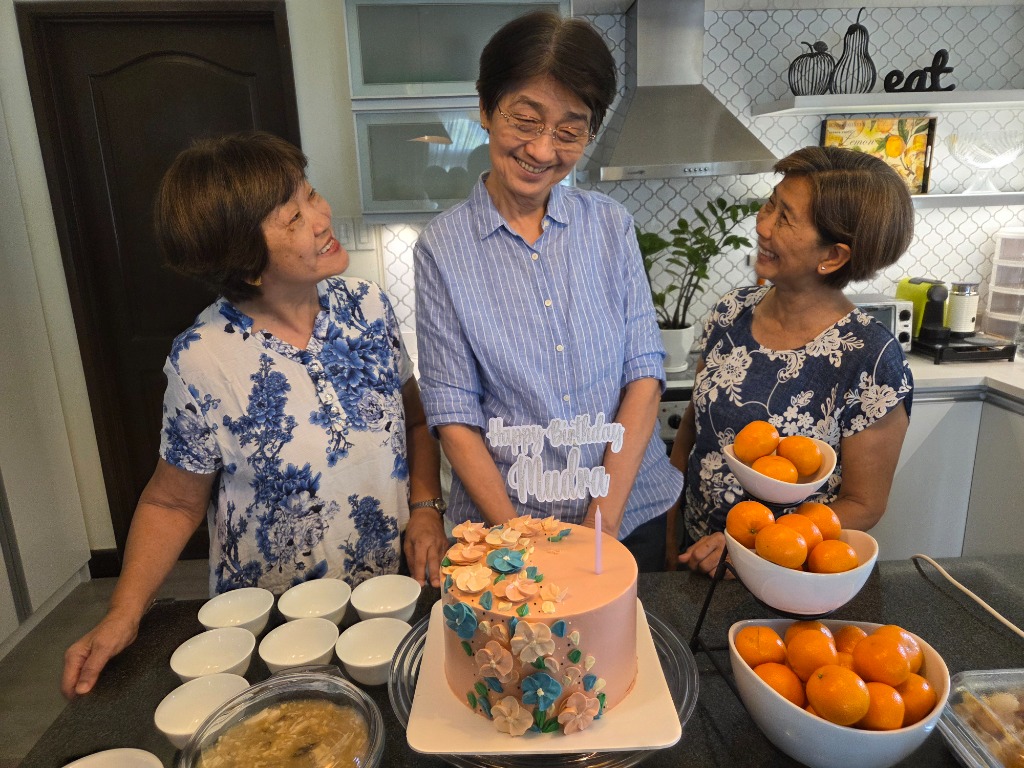 Olivan Sisters looking lovingly at the Happy Birthday Mudra birthday cake