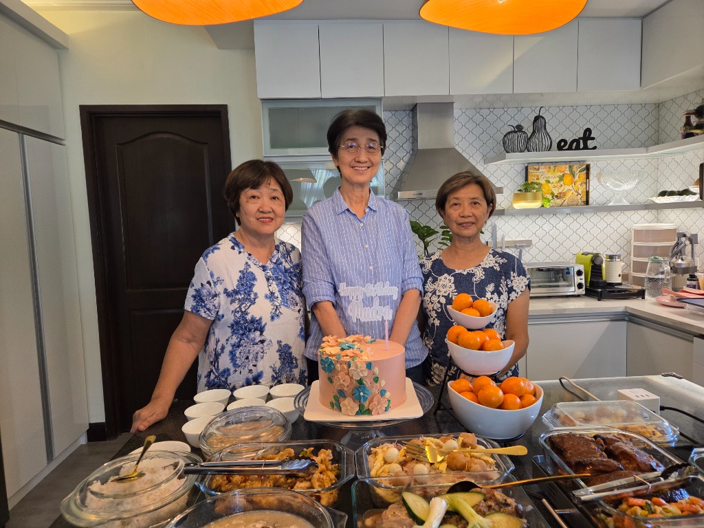 Olivan Sisters posing with the birthday cake and full celebration food spread