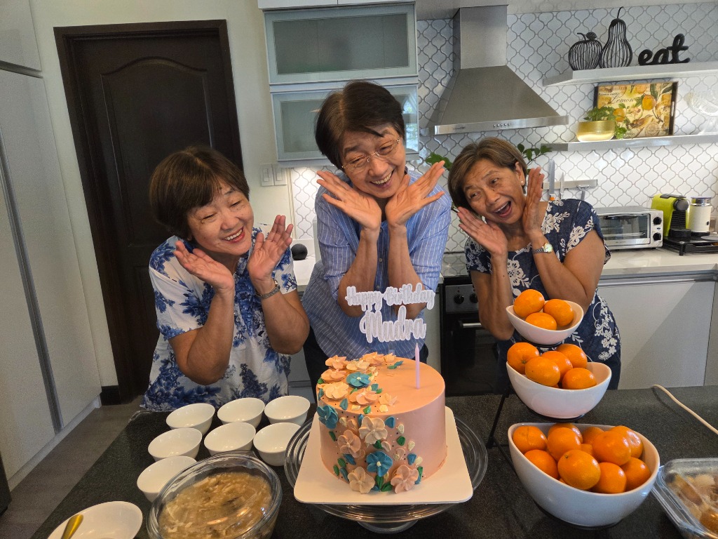 Olivan Sisters striking a fun pose with the floral birthday cake